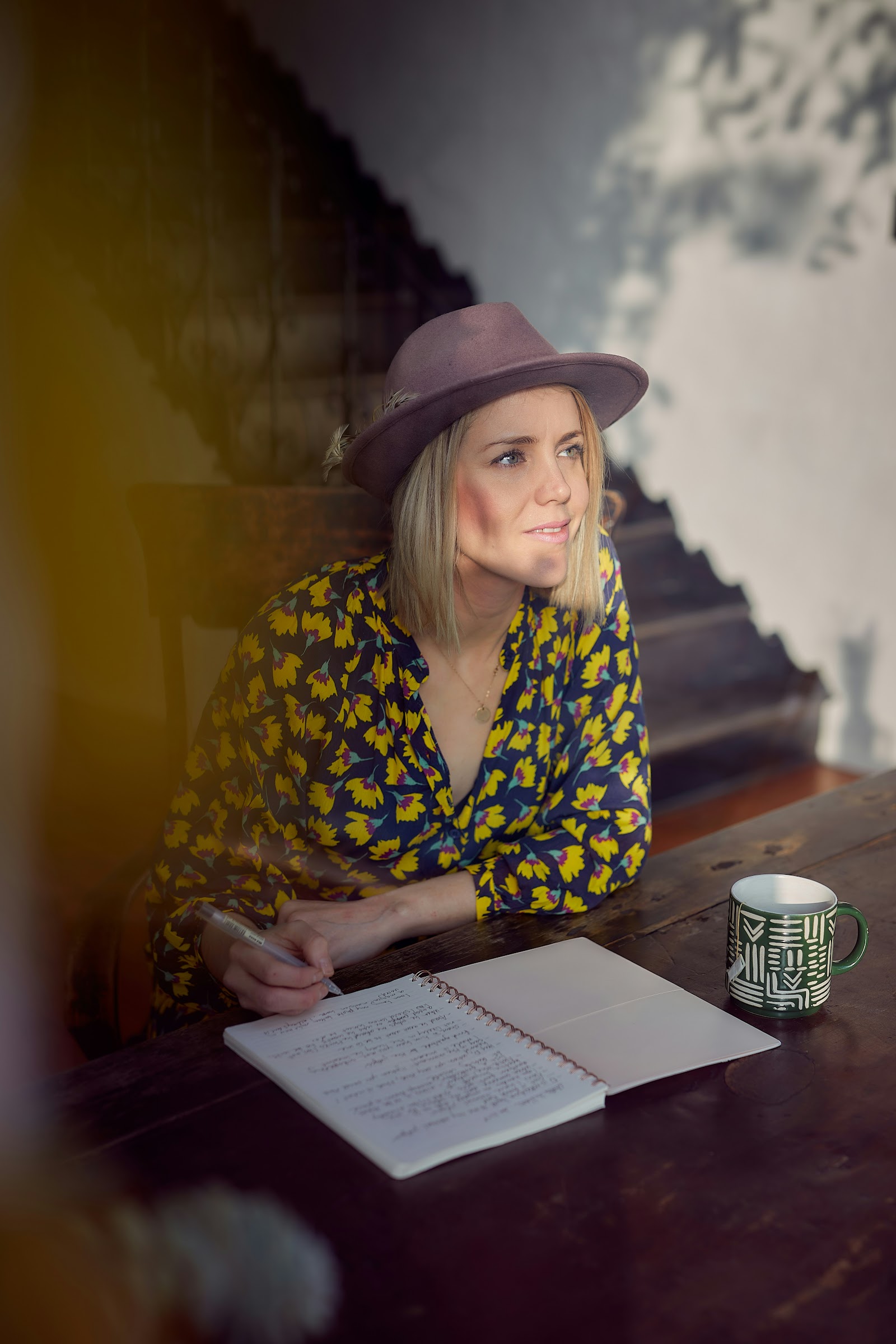 An author at her desk, pausing to think over a notebook